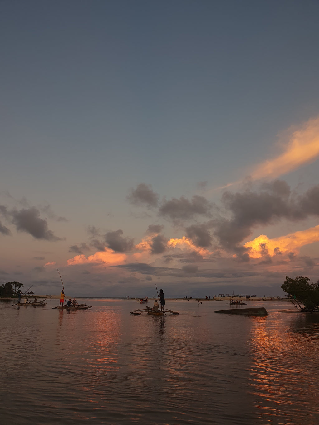 Sunset over water with a boat and trees in the background