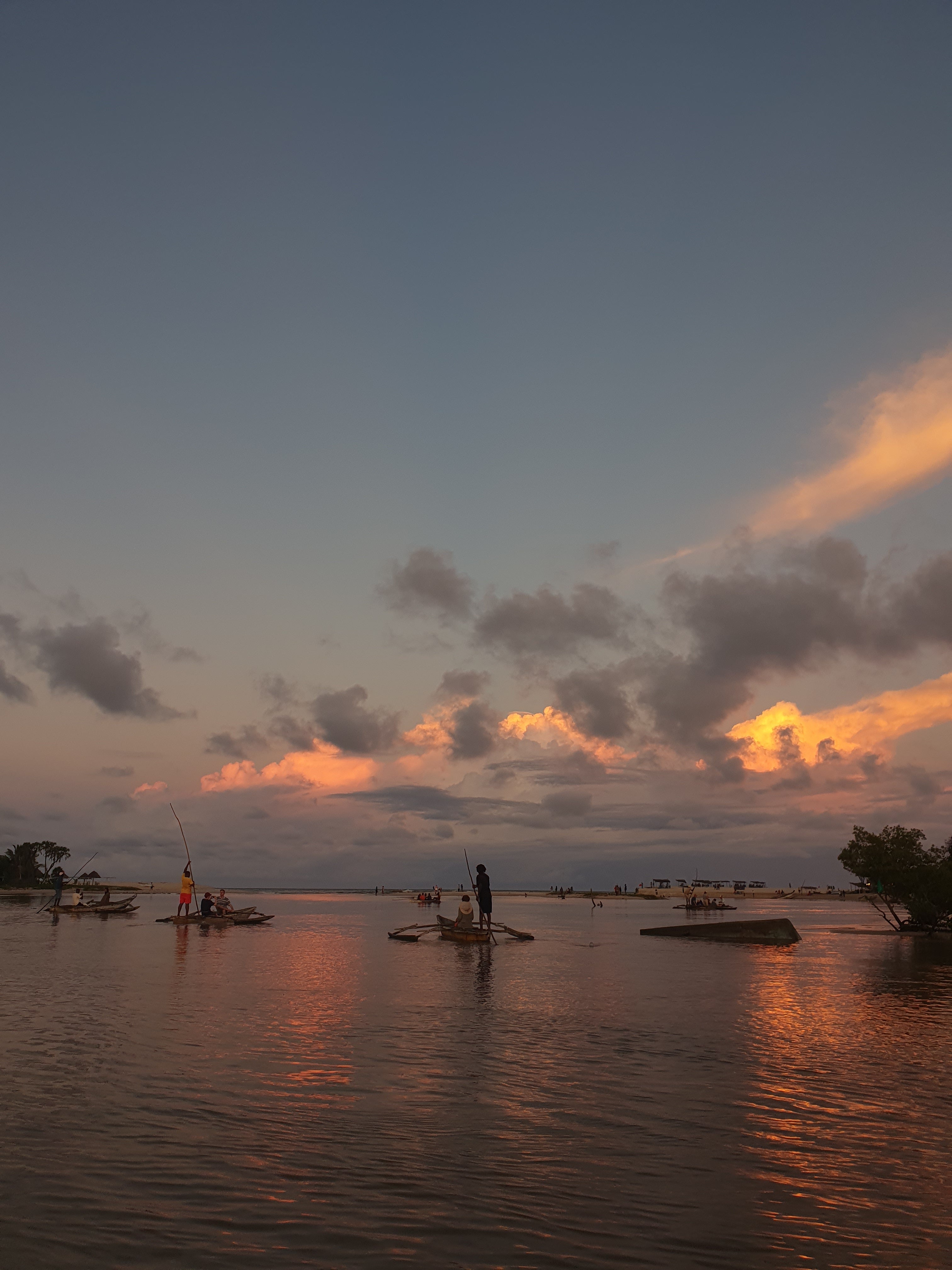 Sunset over water with a boat and trees in the background